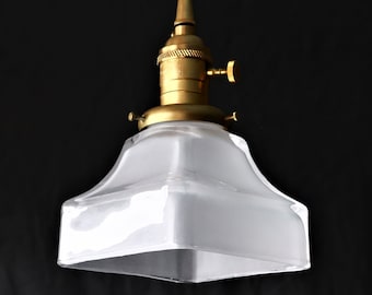 May include: A brass pendant light fitting with a frosted glass square shade. The shade has a slightly rounded top and bottom.