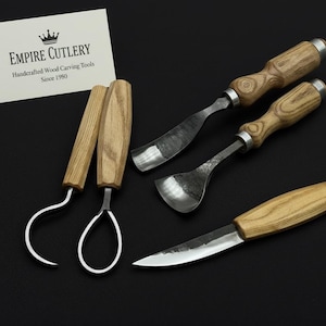 May include: A set of handcrafted wood carving tools, including a knife, gouges, and hook knives. The tools have wooden handles and metal blades. A business card with the text "EMPIRE CUTLERY" is in the background.