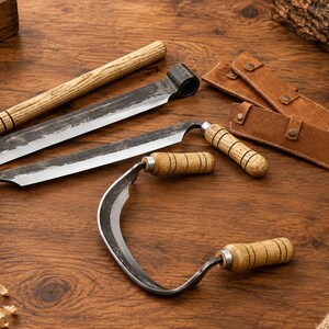 May include: Three woodworking drawknives with dark metal blades and light brown wooden handles featuring black ring details. Two tools have straight blades, one has a curved blade, and two brown leather protective sheaths are included.