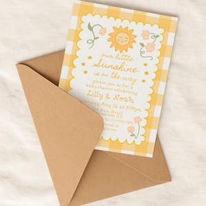 May include: A baby shower invitation with a yellow gingham pattern and a smiling sun illustration. The text reads "our little sunshine is on the way" with details for Lilly & Noah's baby shower, including the date, time, and location, inside a brown envelope.