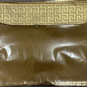 May include: A gold-coloured, rectangular storage pouch with a clear front. The top flap features a gold geometric pattern. The edges are trimmed with a gold border, creating a decorative and functional accessory.