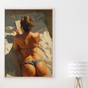 Puede incluir: Una impresión artística enmarcada representa a una persona leyendo un libro en una cama. La persona lleva un top de bikini negro y una braguita de bikini gris. La obra de arte está pintada en tonos cálidos, con la luz del sol iluminando la escena.