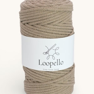 May include: A spool of beige macrame cord with a white label wrapped around it. The label features the brand name "Loopello" and the tagline "live love loop" in black text, along with a needle and thread logo.