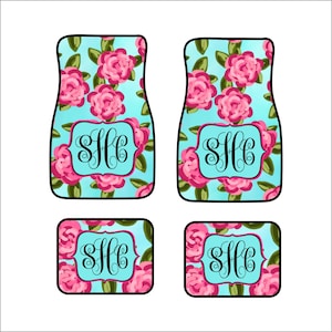 May include: Set of four car floor mats with a floral design. The mats are turquoise blue with pink roses and green leaves. The mats have a black monogram "SHC" in the center.