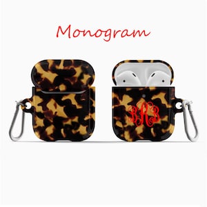May include: A tortoiseshell patterned Airpods case with a red monogram "BB3" and a silver carabiner clip.