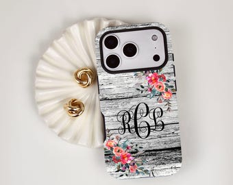 May include: A rectangular phone case featuring a weathered gray wood grain pattern, decorated with vibrant pink and orange floral clusters at the top and bottom corners, and a black script monogram with the letters RCL in the center.