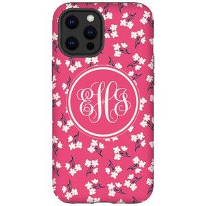 K&ouml;nnte beinhalten: Eine rosa Handyh&uuml;lle mit einem wei&szlig;en Blumenmuster und einem wei&szlig;en Monogrammkreis mit den Buchstaben "HLS" in einer Schriftart.
