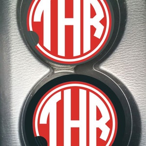 May include: Two black and red car coasters with the letters "THR" in white.