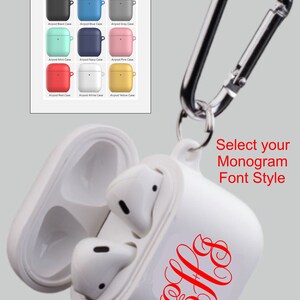 May include: White Airpod case with a red monogram and a silver carabiner clip. The case is available in nine colors, including black, blue, grey, mint, navy, pink, red, white, and yellow.