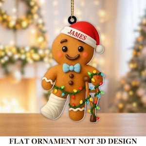 May include: A gingerbread man Christmas ornament with a red Santa hat that says "JAMES". The gingerbread man has a blue bow tie, a leg cast, and a crutch wrapped in Christmas lights. The ornament is a flat design.