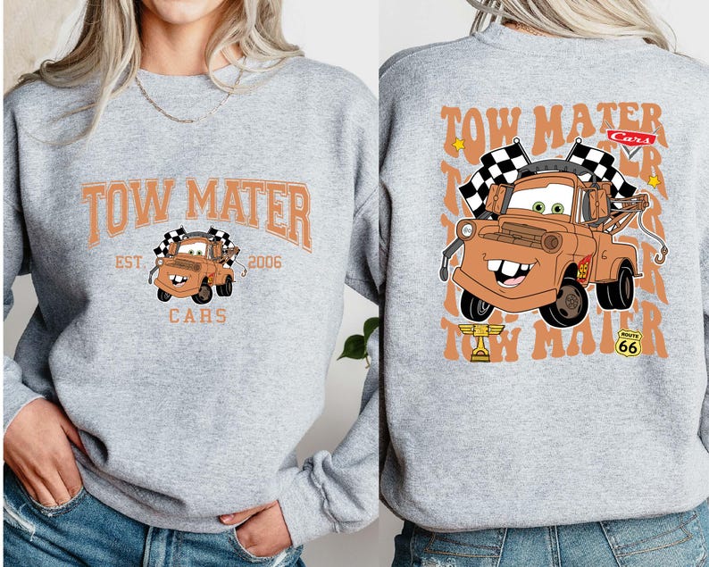 Peut inclure: Un sweat-shirt gris clair avec une image de dessin anim&eacute; de Martin la d&eacute;panneuse du film Cars. Le devant affiche "TOW MATER" au-dessus de l'image, avec "EST. 2006" et "CARS" en dessous. Le dos pr&eacute;sente Martin avec des drapeaux &agrave; damier.