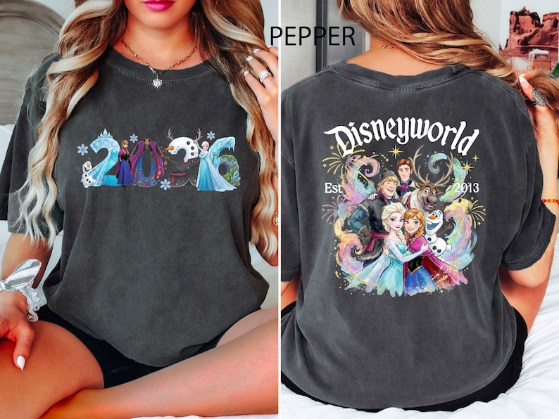 K&ouml;nnte beinhalten: Dunkelgraues T-Shirt mit einer farbenfrohen Grafik von Frozen-Charakteren und dem Jahr 2016 auf der Vorderseite. Auf der R&uuml;ckseite des Shirts steht "Disneyworld Est. 2013" mit weiteren Frozen-Charakteren.