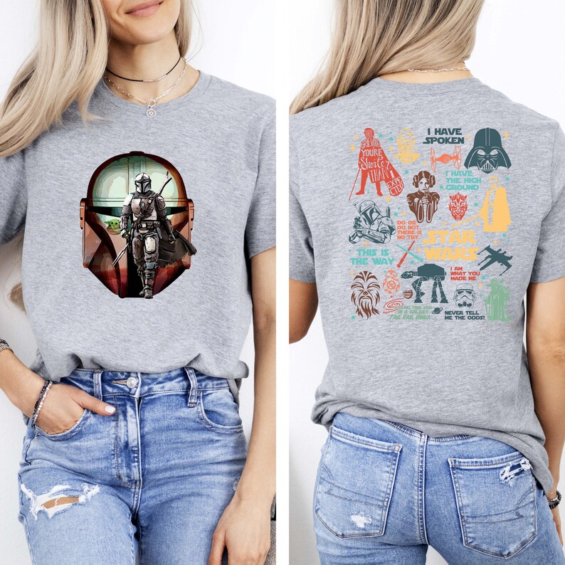 May include: A heather gray t-shirt featuring a graphic of The Mandalorian on the front. The back of the shirt displays various Star Wars character illustrations and phrases, including "I Have Spoken" and "This is the Way."