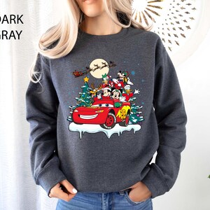 K&ouml;nnte beinhalten: Dunkelgraues Sweatshirt mit festlichem Design mit Disney-Figuren in einem roten Rennwagen, einem Weihnachtsbaum und einem Vollmond. Der Text "DARK GRAY" befindet sich in der oberen linken Ecke. Der Pullover ist ein bequemer, l&auml;ssiger Stil.