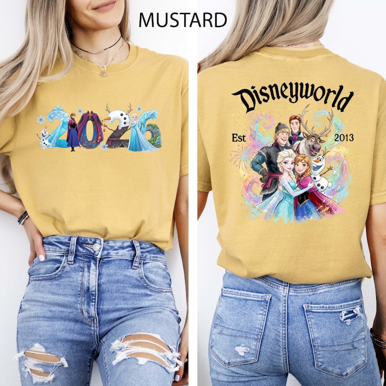 K&ouml;nnte beinhalten: Senffarbenes T-Shirt mit dem Text "2026" und Frozen-Charakteren auf der Vorderseite. Auf der R&uuml;ckseite steht "Disneyworld Est 2013" mit einer Grafik von Charakteren aus dem Film Frozen.