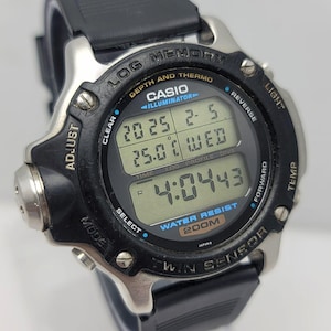 May include: A black and silver Casio digital watch with a black rubber strap. The watch face displays the time, date, and temperature. The watch has multiple buttons and features, including depth and thermo sensors. The watch is water resistant to 200m.