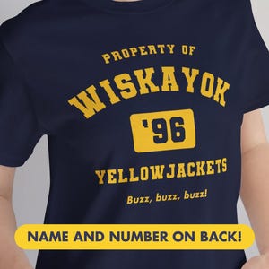 以下が含まれることがあります： 紺色のTシャツ。黄色の文字で「PROPERTY OF WISKAYOK '96 YELLOW JACKETS Buzz, buzz, buzz!」と書かれています。下部には「NAME AND NUMBER ON BACK!」と書かれた黄色のバナーがあります。