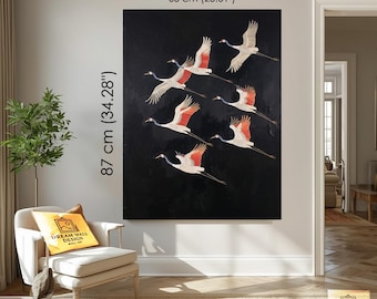 Può includere: Una grande opera d'arte su tela nera con uno stormo di gru bianche e rosse in volo. L'opera misura 87 cm di altezza e 65 cm di larghezza. L'opera è esposta su una parete bianca.