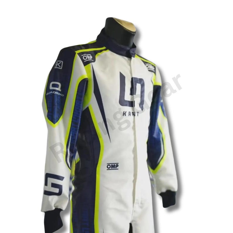 May include: White and navy blue racing suit with yellow accents. The suit features the text "KART" and the brand "OMP". The suit has a high collar and black cuffs. The suit is designed for kart racing.