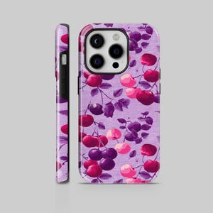 Può includere: Custodia per telefono con un vivace motivo a ciliegie. Il design presenta grappoli di ciliegie rosse, rosa e viola con foglie verdi su uno sfondo lilla chiaro. La custodia è mostrata frontalmente e lateralmente.
