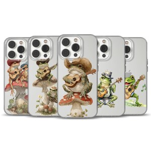 May include: A collection of phone cases featuring watercolor illustrations of frogs playing guitars. The frogs are depicted in various poses, some wearing hats, and are set against a backdrop of mushrooms and musical notes. The cases are clear with a glossy finish.