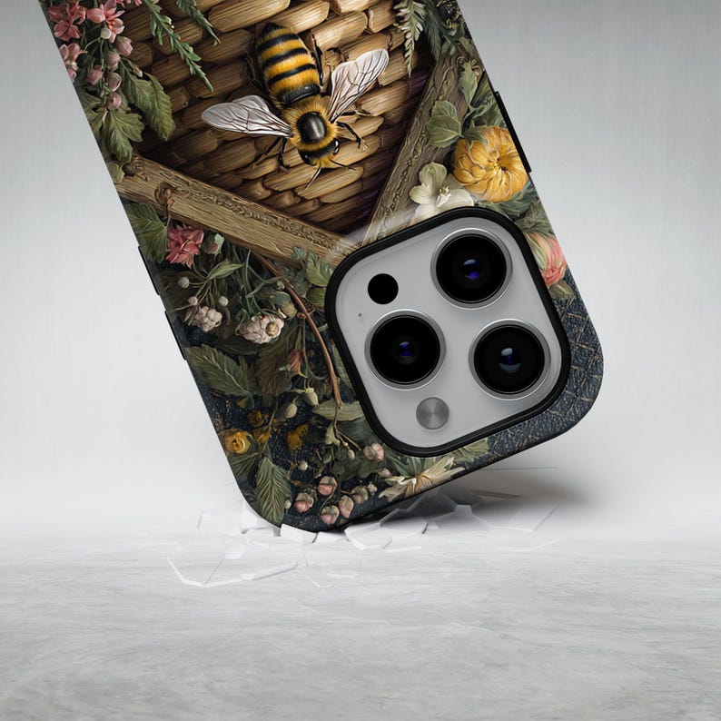 May include: A phone case featuring a detailed illustration of a bee hovering near a woven basket, surrounded by flowers and foliage. The case has a dark background with a textured appearance and a camera cutout.