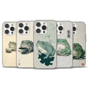 May include: A collection of phone cases featuring illustrations of frogs in various poses. The cases showcase a range of designs, including frogs with bowls, on leaves, and holding objects, all in a Japanese art style.