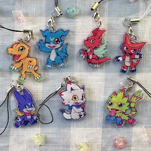 Pode incluir: Coleção de amuletos de personagens coloridos em estilo anime. Cada amuleto apresenta um design de criatura único com cores vibrantes como laranja, azul, vermelho, roxo, branco e verde. Eles são presos a cordões pretos com fechos prateados.