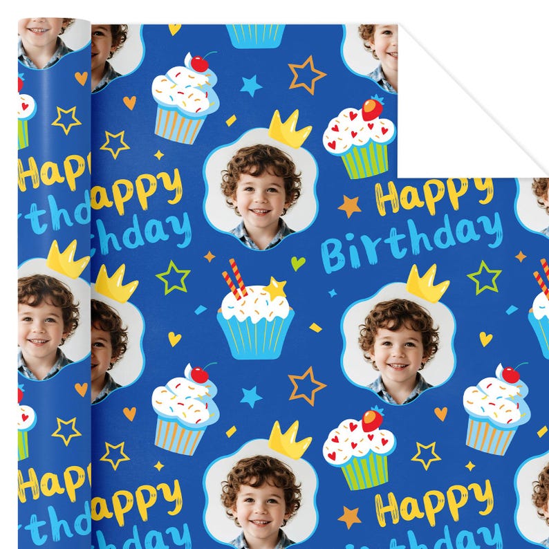 May include: Blue wrapping paper with a repeating pattern of cupcakes, stars, crowns, and the text "Happy Birthday." The design includes a photo of a smiling child. The cupcakes have white frosting and red cherries.