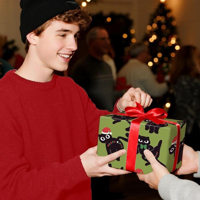 May include: A wrapped gift box with a green background and a pattern of black cats wearing Santa hats and bow ties. The box is tied with a red ribbon and bow. The text "Merry Xmas" is on the box.