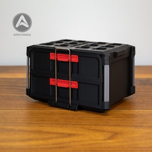 May include: Black storage organizer with two drawers and a top compartment. The drawers have red handles, and the organizer has a metal handle. The logo "APEX MAKES" is in the top left corner. The organizer is on a wooden surface.
