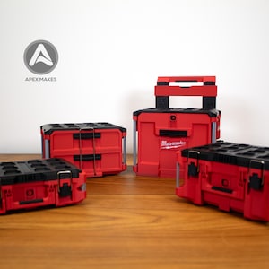 May include: A collection of red and black toolboxes and storage containers. The image features several boxes of varying sizes, including one with a handle. The brand name "Milwaukee" is visible on one of the boxes. The logo "Apex Makes" is in the background.