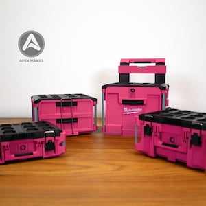 May include: A collection of pink and black toolboxes and storage containers. The containers have black tops and handles, with the brand name "Milwaukee" visible on one. The logo "Apex Makes" is in the background.