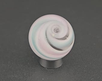 May include: A spherical glass marble featuring a swirling pattern of pastel pink, light blue, and white colors. The surface of the marble is smooth and glossy, with the spiral design converging toward a central point on the top of the sphere.