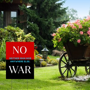 May include: A yard sign with the word "NO" in white on a red background, above the text "NEITHER IRAN NOR ANYWHERE ELSE." and the word "WAR" in white on a black background. The sign is in a grassy yard with a flower cart.