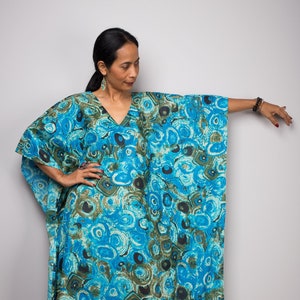 May include: A long, flowing blue and green kaftan with a swirling, abstract pattern. The kaftan has a V-neck and long sleeves.