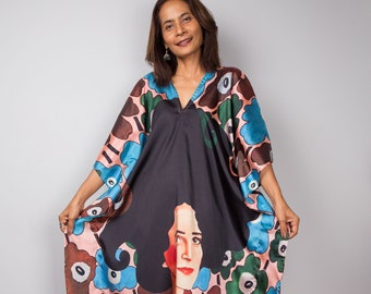 May include: A long, flowing dress with a V-neck and a striking floral and portrait design. The dress has a black background with large blue, brown, and green flowers. A woman's face is displayed on the front. The model is wearing yellow sandals.