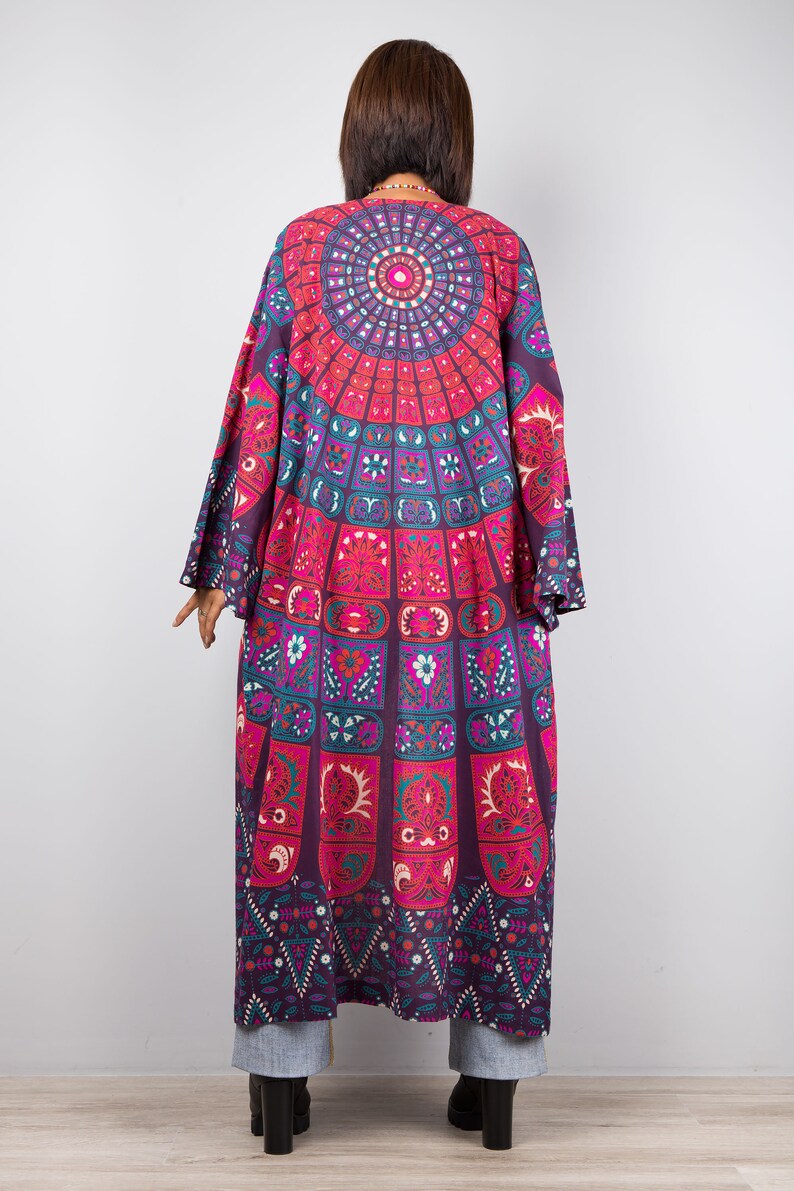 Pu&ograve; includere: Un kimono lungo e fluido di colore viola e rosa con un motivo mandala colorato. Il kimono ha maniche larghe e una vestibilit&agrave; rilassata.
