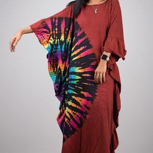 May include: A long, rust-colored, tie-dye dress with a rainbow swirl design. The dress has a loose, flowing fit and a ruffled hem.