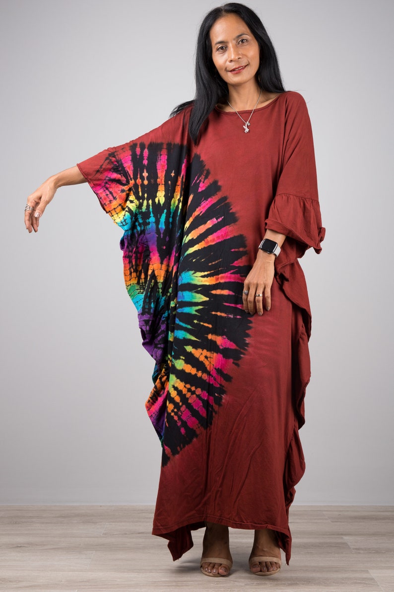 May include: A long, rust-colored, tie-dye dress with a rainbow swirl design. The dress has a loose, flowing fit and a ruffled hem.