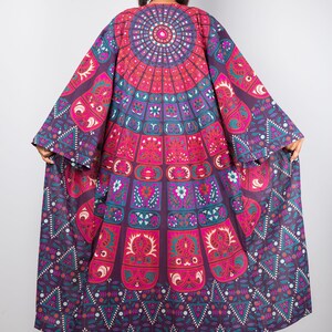 Pu&ograve; includere: Un kimono lungo e fluido di colore viola e rosa con un motivo a mandala. Il kimono ha una manica larga e fluida e una scollatura a V profonda.