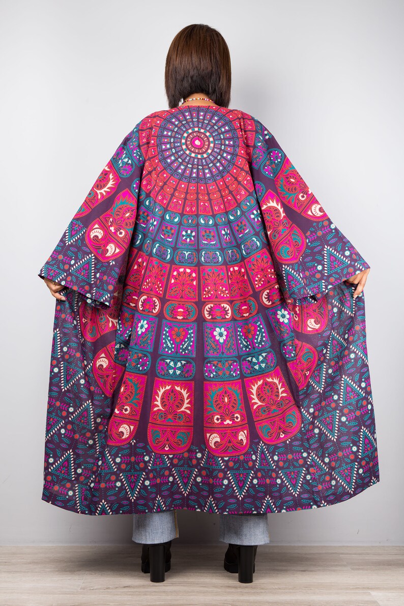 Pu&ograve; includere: Un kimono lungo e fluido di colore viola e rosa con un motivo a mandala. Il kimono ha una manica larga e fluida e una scollatura a V profonda.