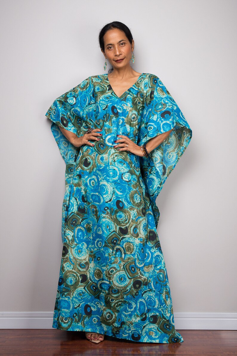 May include: A long, flowing blue and green kaftan with a circular pattern. The kaftan has a V-neck and wide sleeves.