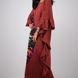 May include: A long, rust-colored maxi dress with a tie-dye design in rainbow colors. The dress has a ruffled hem and ruffled sleeves.