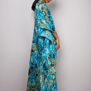 May include: A long, flowing blue and green patterned dress with a loose fit. The dress has a V-neckline and a wide, flowing skirt.
