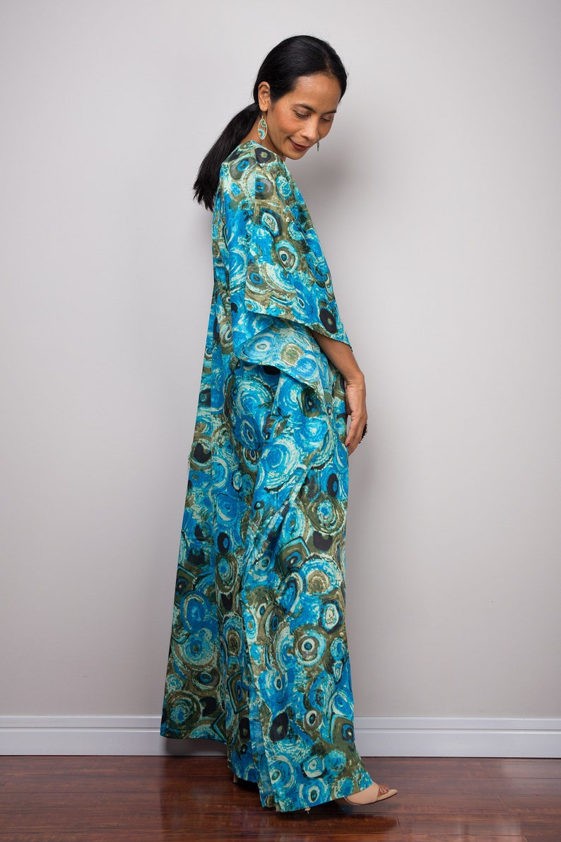 May include: A long, flowing blue and green patterned dress with a loose fit. The dress has a V-neckline and a wide, flowing skirt.
