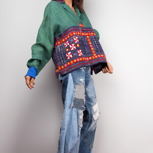 K&ouml;nnte beinhalten: Eine Frau tr&auml;gt eine gr&uuml;ne und blaue bestickte Jacke mit einem blauen Jeans-Patchwork-Rock und gelben Schuhen mit Absatz.