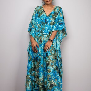 May include: A woman wearing a long, blue and green kaftan with a swirling pattern. The kaftan has a V-neck and long sleeves.