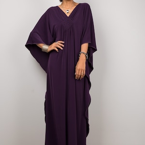 May include: A long, flowing purple kaftan dress with a V-neckline and a gathered waist. The dress has a relaxed fit and is made of a soft, comfortable fabric.