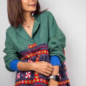 K&ouml;nnte beinhalten: Eine Frau tr&auml;gt ein gr&uuml;n-blau-rot gemustertes Hemd mit einer blau-wei&szlig;en Uhr am Handgelenk.